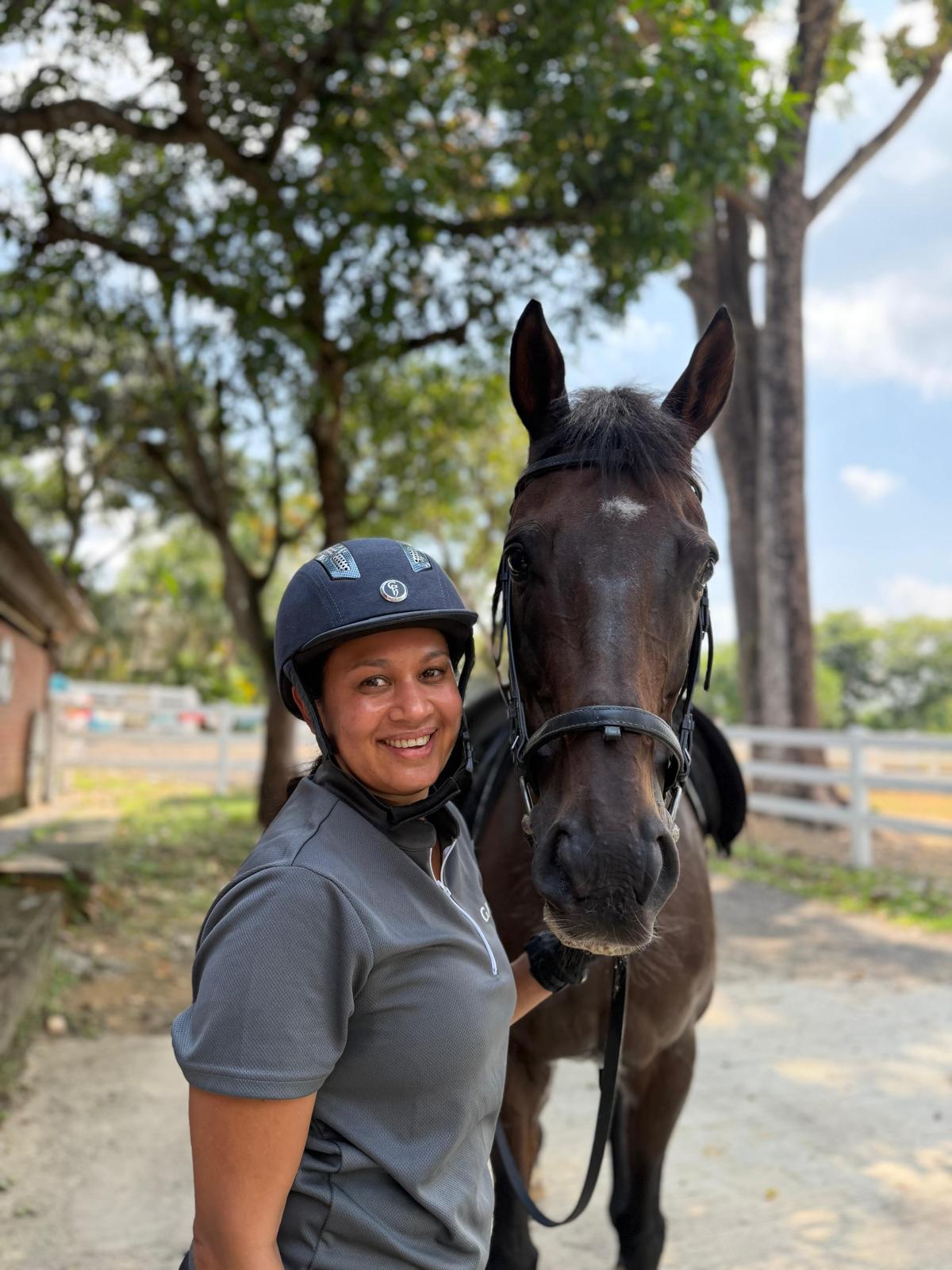 A smiling rider standing with her horse